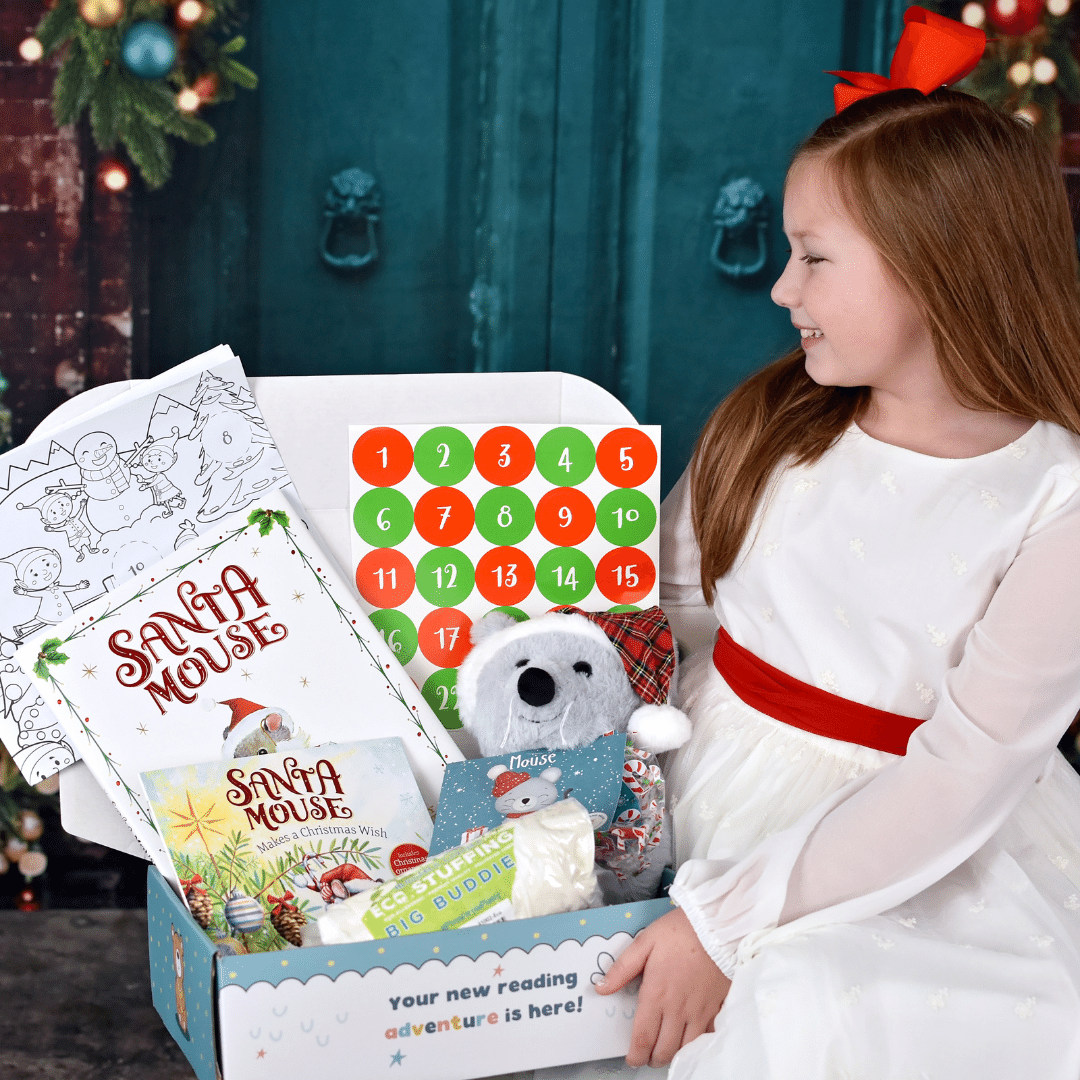 Girl holds open Christmas Mouse Book and Bear box