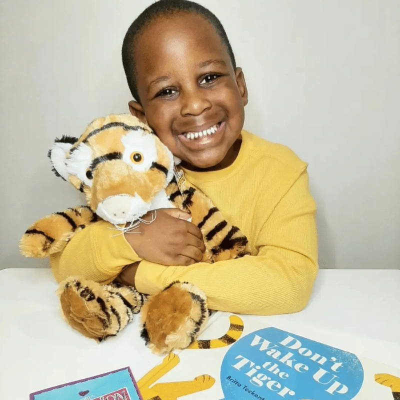 Boy hugs the tiger he crafted from Book and Bear