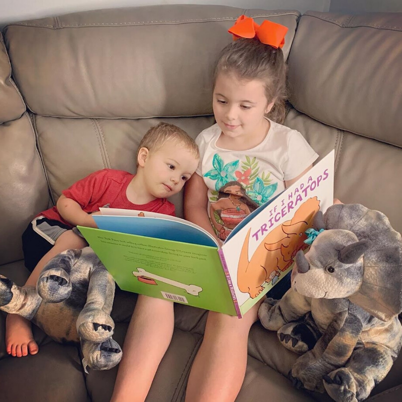 Big sister reading Triceratops book to little brother with Stuffed Plush Triceratops Dinosaurs from Book and Bear