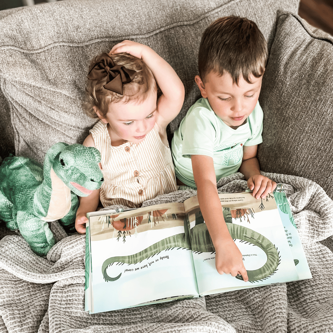 Brother and Sister Read a dinosaur book with their newly built dinosaur friend. | Book and Bear